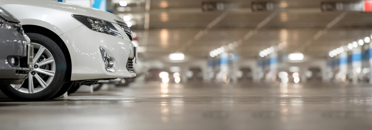 Garage-Epoxy-Flooring This image shows a white car parked in a parking lot with polished concrete.
