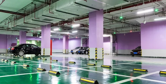 Our-Garage-Epoxy-Installation-Process This image shows a commercial parking area that has a green epoxy color and white lines.