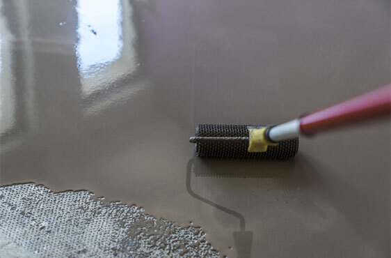 Epoxy Floor Coating Contractors This image shows a floor being painted with a roller brush.