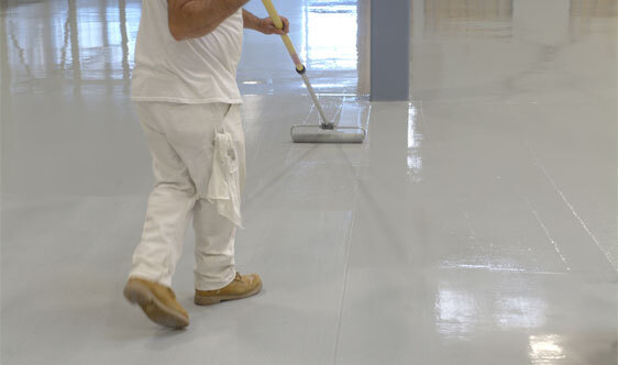 Industrial Epoxy Floor Coating This image shows a man applying epoxy paint on an industrial floor.